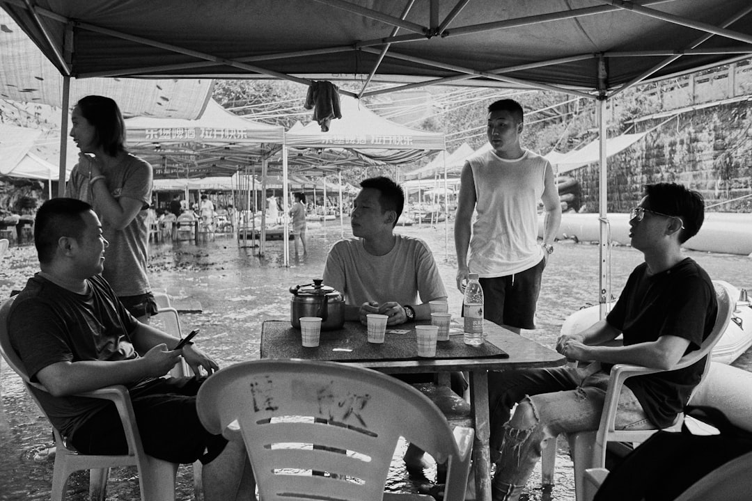 grayscale photo of men sitting on bench