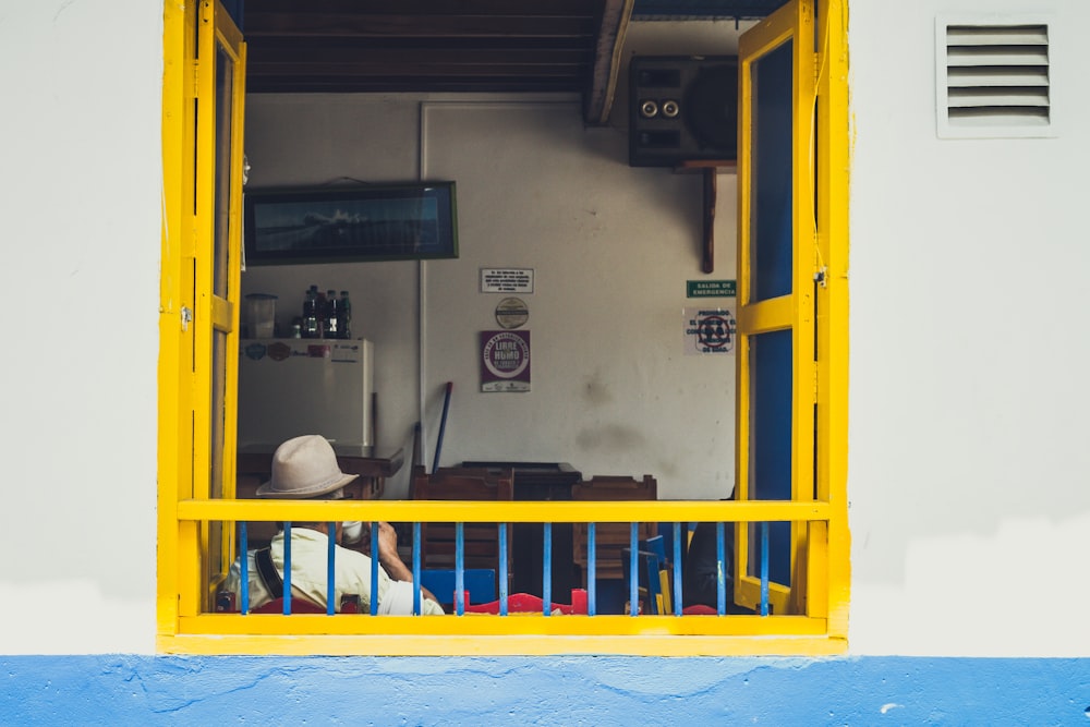 man sitting near window wearing cowboy hat