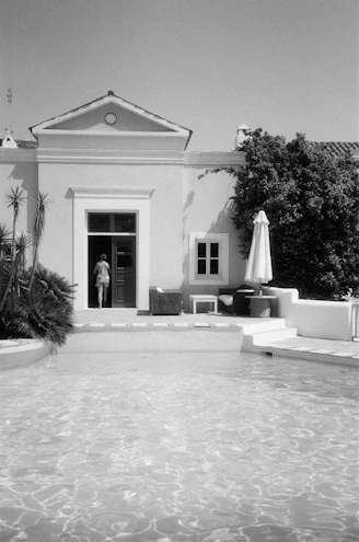 grayscale photo of concrete house near trees