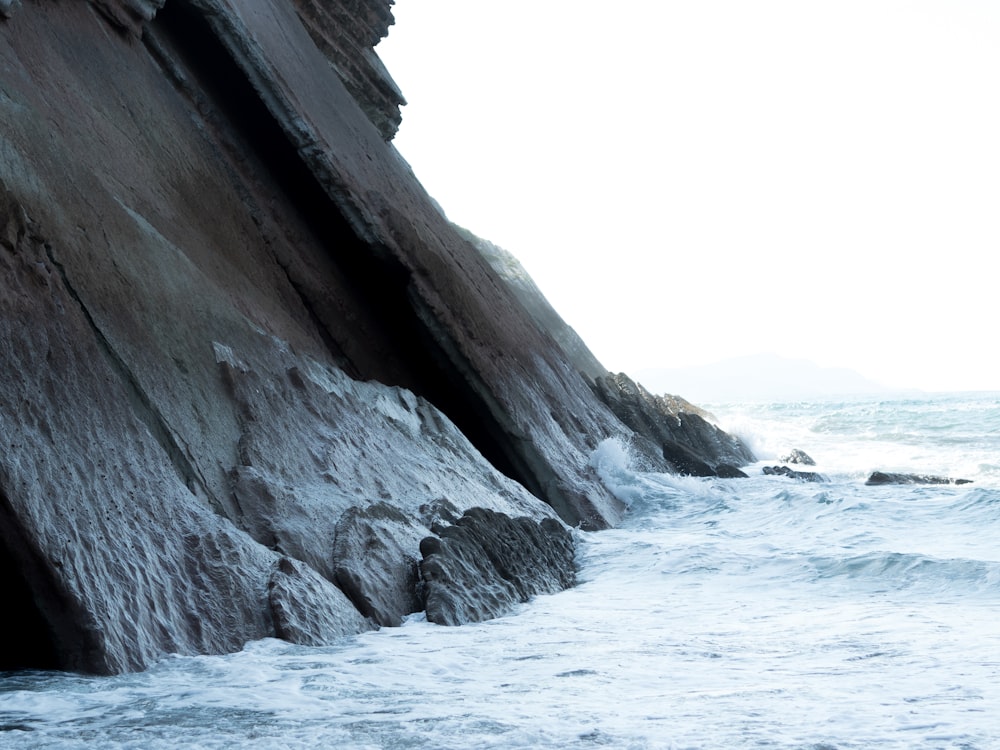 Una persona parada en la cima de una roca junto al océano