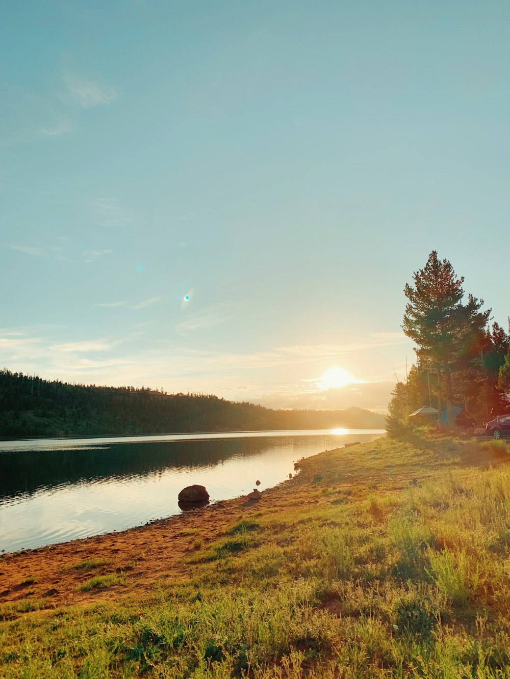 the sun is setting over a small lake