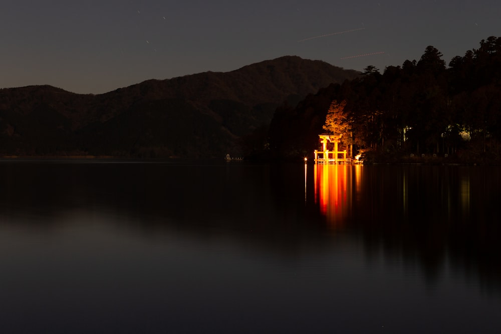 a body of water at night with mountains in the background