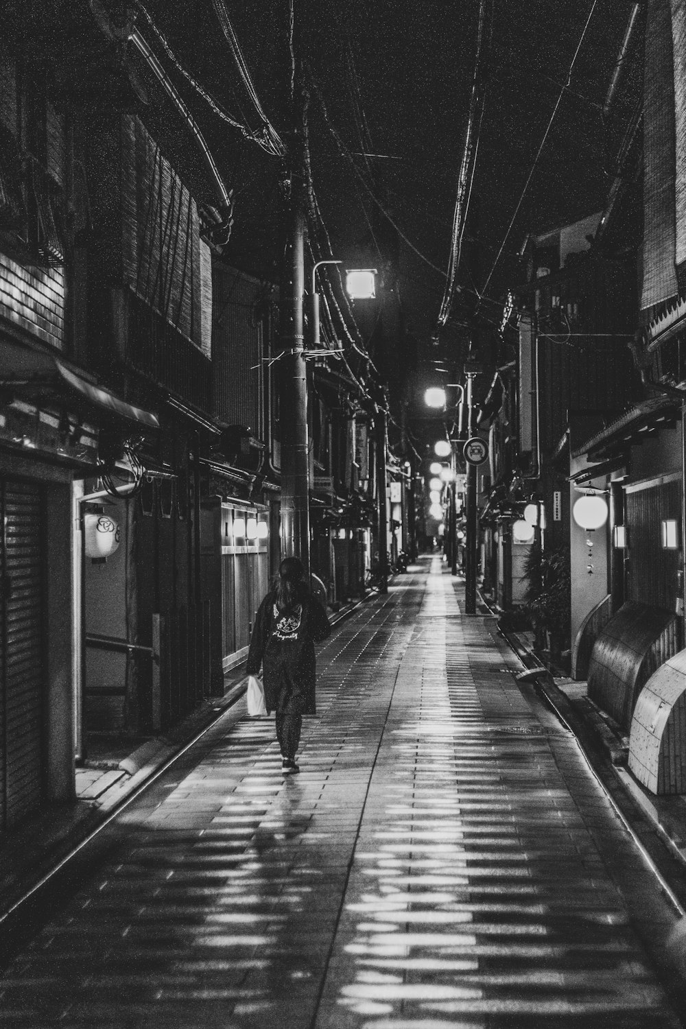 a black and white photo of a person walking down a street