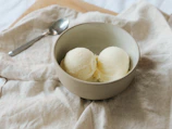 Homemade vanilla ice cream scoops in a bowl with mint garnish.