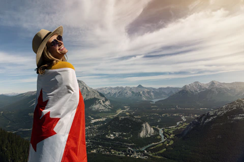smiling woman wearing brown hat and sunglasses while holding Canada flag