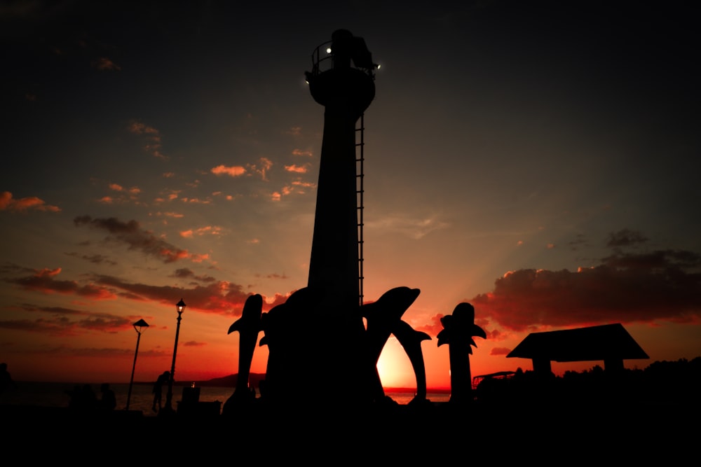 the sun is setting behind a tall tower