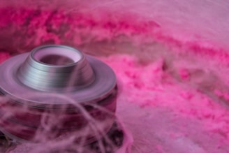 Close-up of a cotton candy machine spinning pink sugar clouds.
