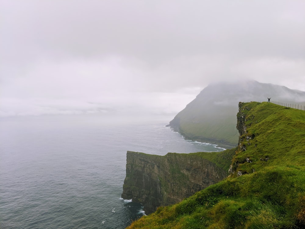 green cliff beside body of water