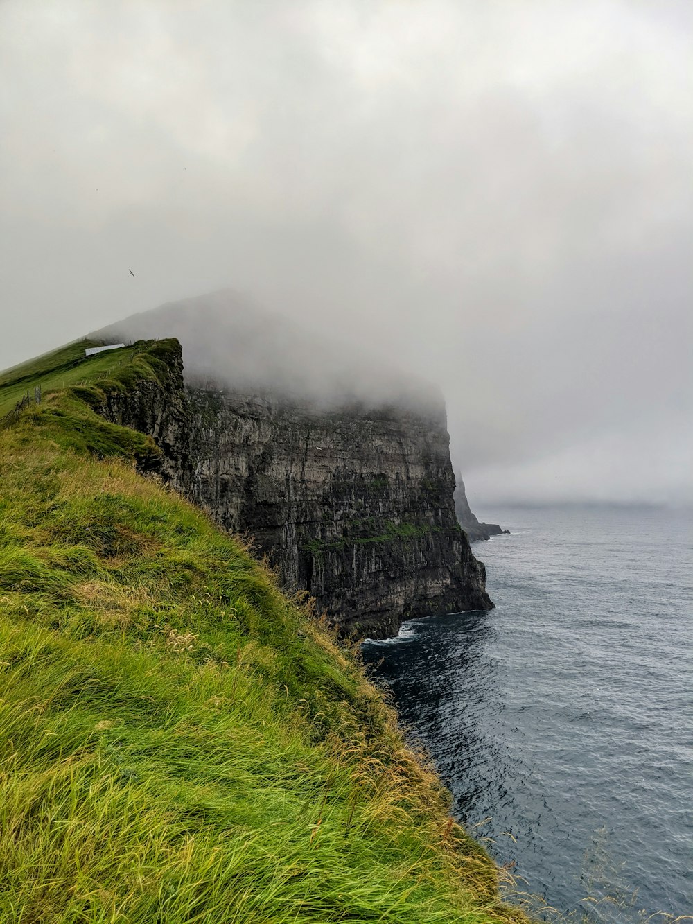 foggy mountain near body of water during daytime