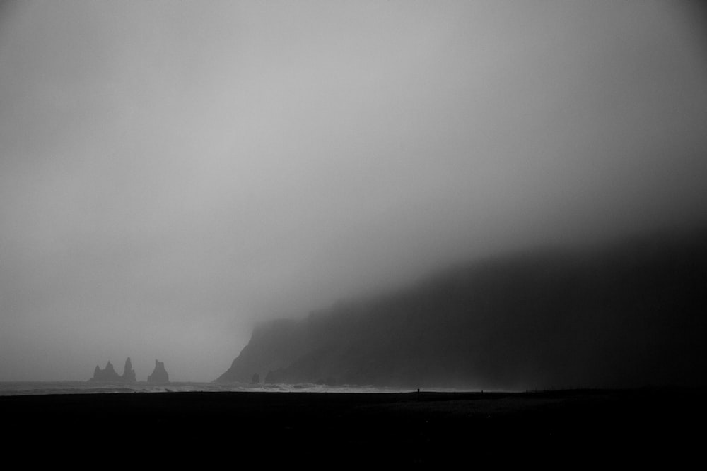 a black and white photo of a foggy beach
