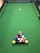 A close-up of a vibrant green pool table felt with colorful billiard balls arranged in a triangle.