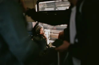 A serene traveler resting comfortably on a train seat, supported by a sleek memory foam neck pillow against a backdrop of soft sunset hues.