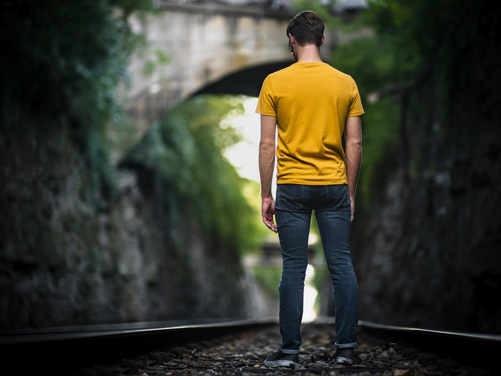 man standing in the middle of train track