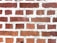 A close-up view of a brick wall with red bricks and gray mortar. The bricks are arranged in a staggered pattern typical of traditional masonry work.