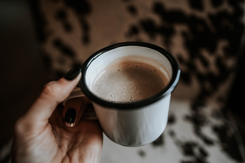 person holding white mug