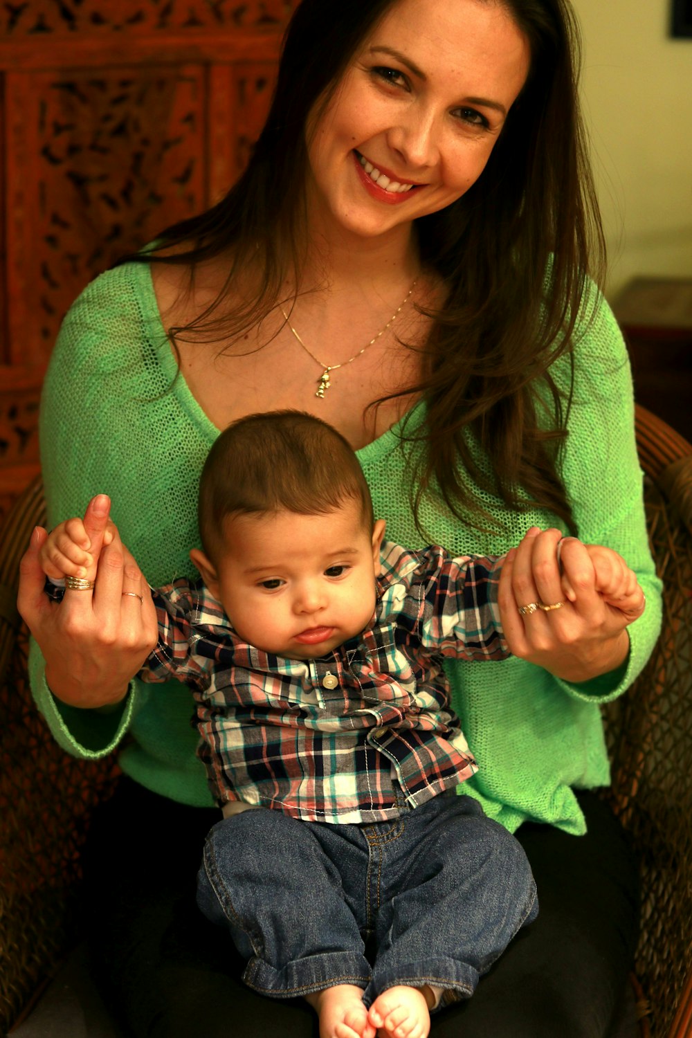 woman holding boy in plaid shirt and blue denim pants