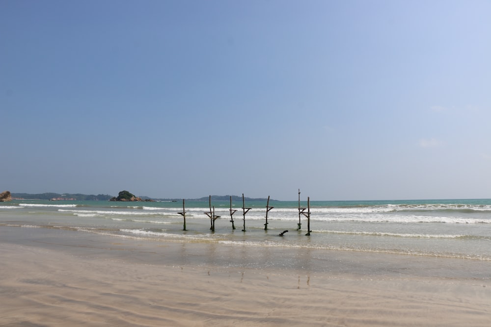 una spiaggia che ha alcuni pali che sporgono dalla sabbia