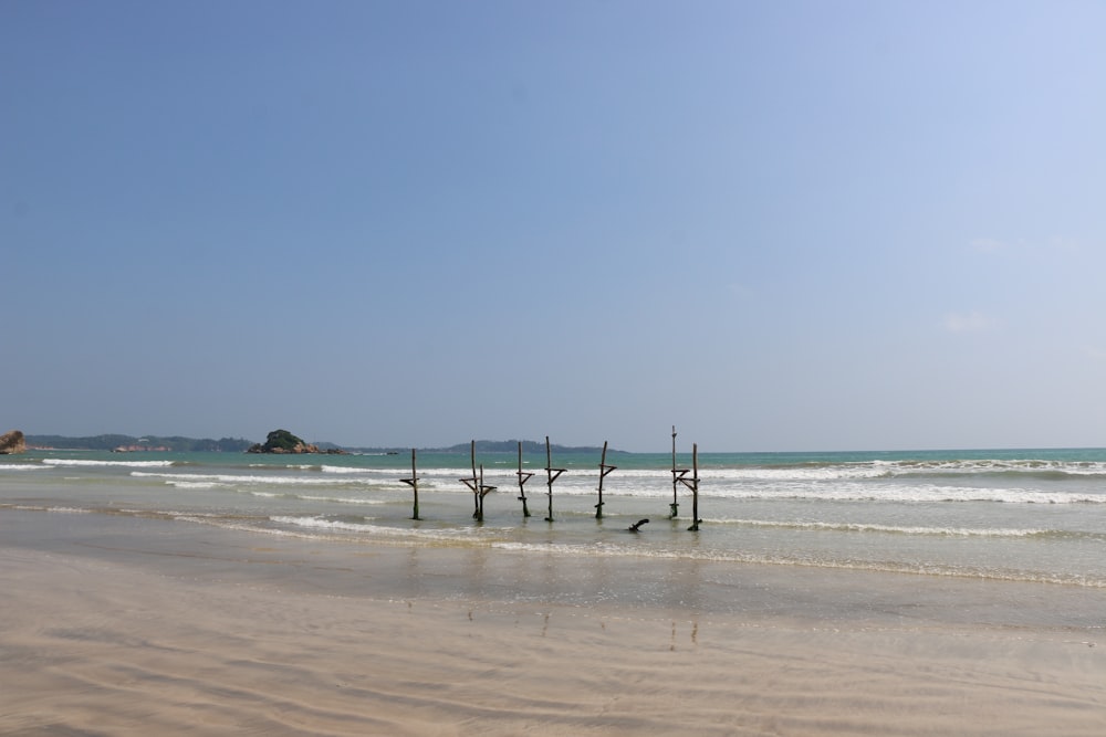 a beach that has some poles sticking out of the sand