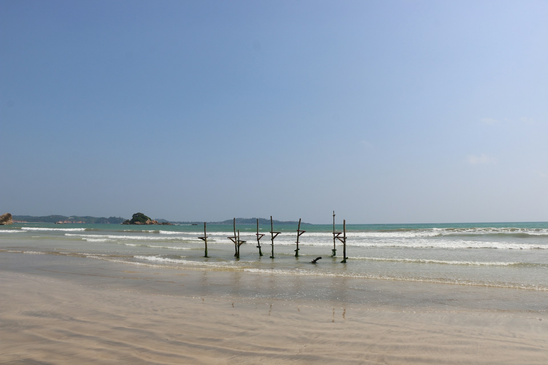 a beach that has some poles sticking out of the sand