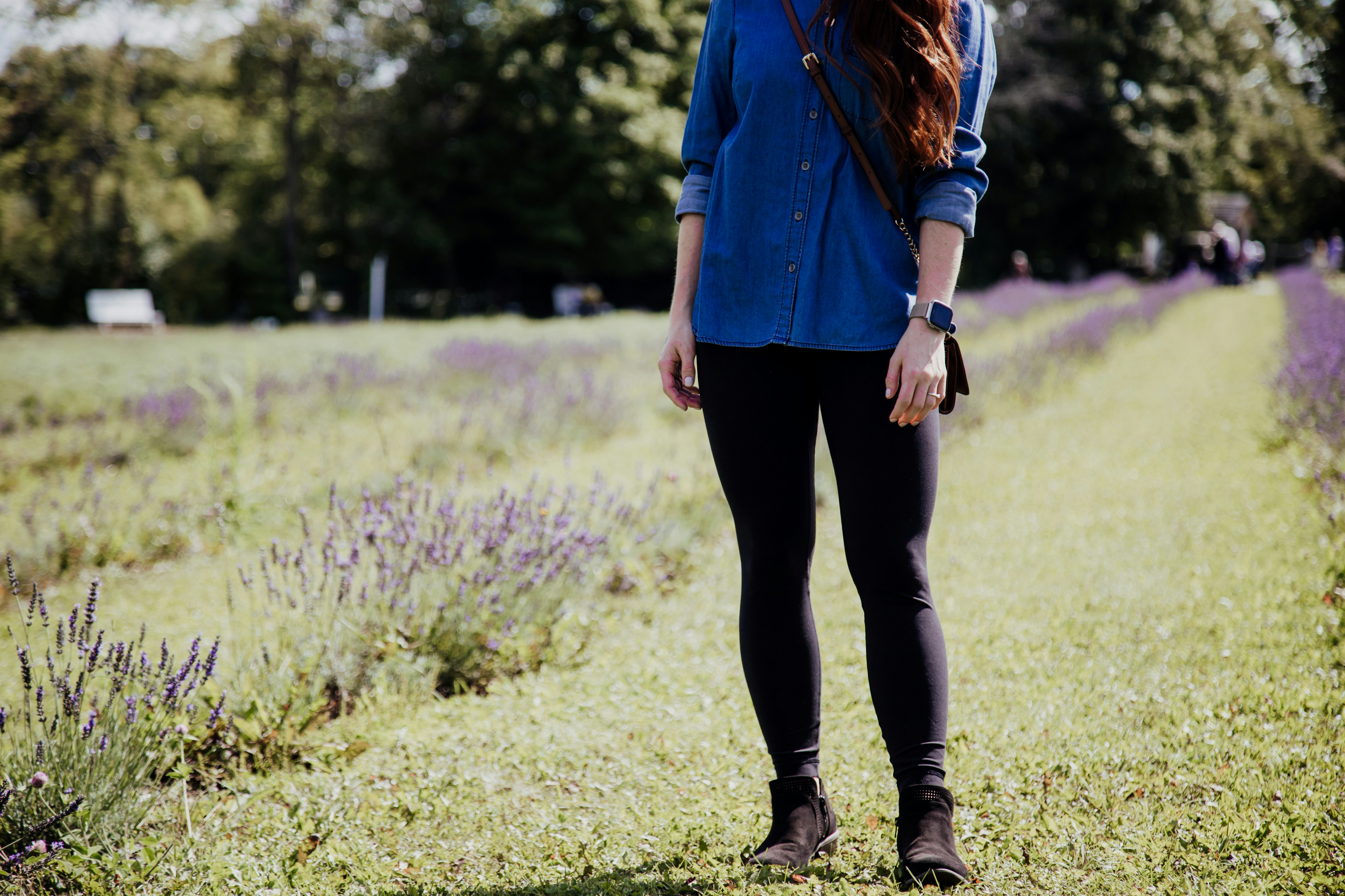woman wearing blue blouse and black leggings standing on grass