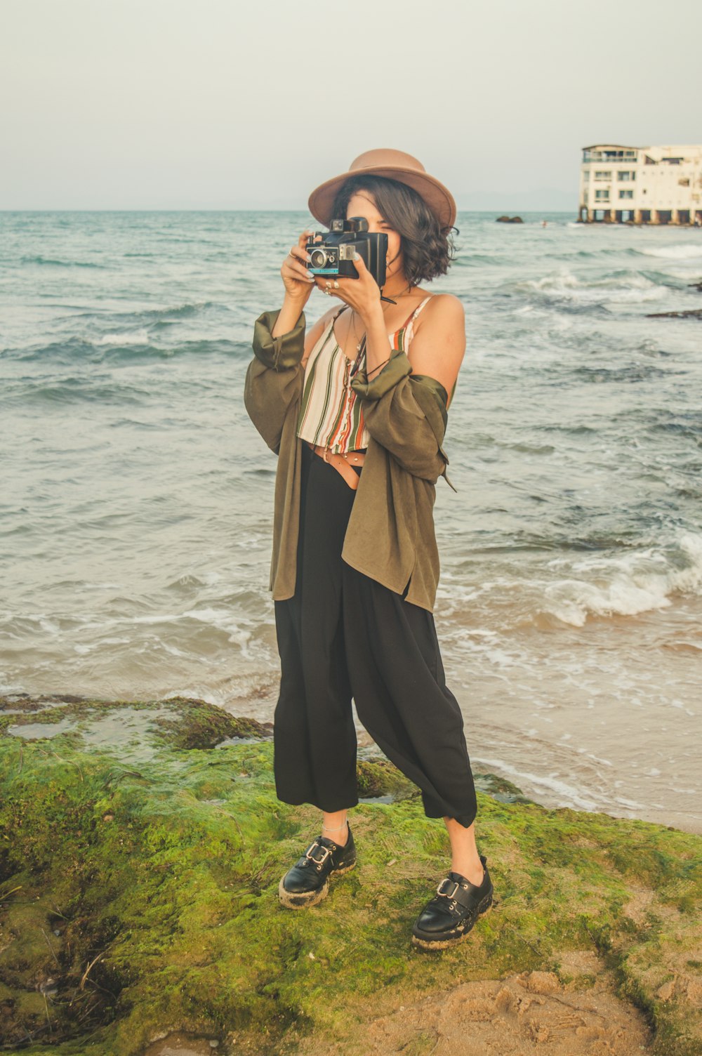 a woman taking a picture of the ocean with a camera