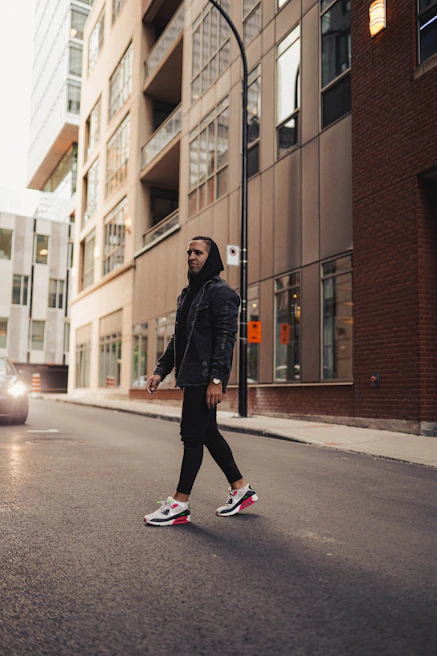Model wearing a vibrant hoodie walking past modern city architecture