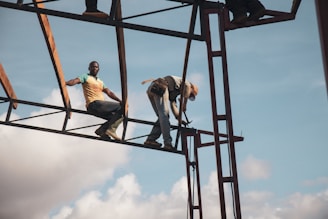 low-angle photography of two men on metal frame tower