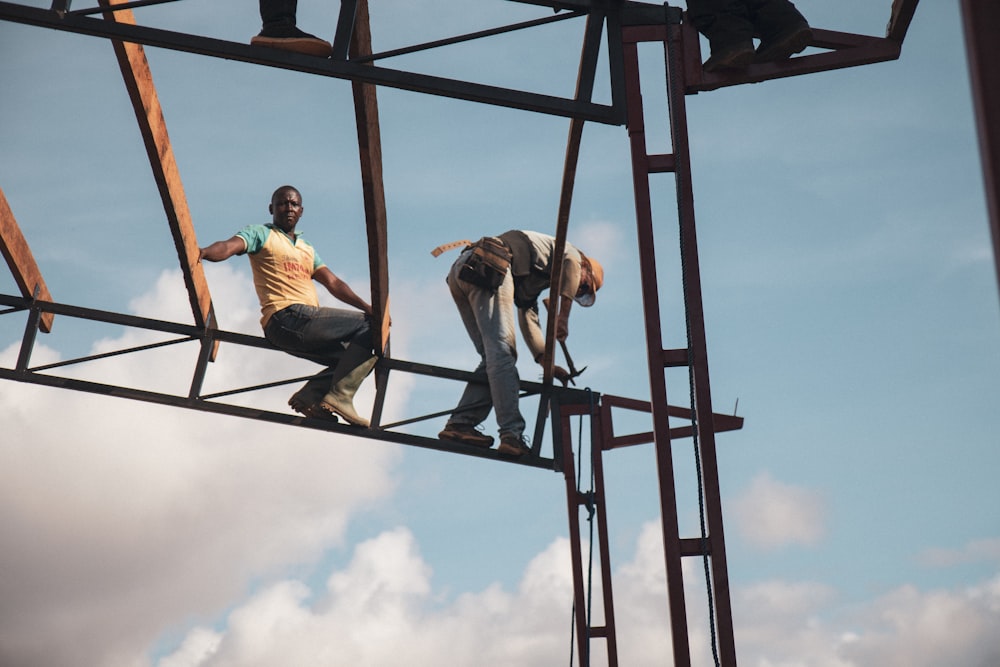 low-angle photography of two men on metal frame tower