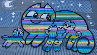 A colorful scene of happy cats in overalls painted by workshop participants, surrounded by art supplies and laughter.