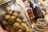 A close-up view of several jars containing pickled and preserved foods, including green olives and sundried tomatoes. The jars are arranged on a surface and include metal lids and visible condensation.