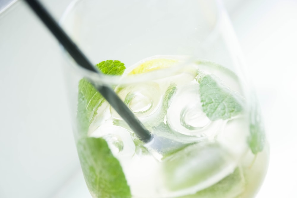 mojito in clear drinking glass with black straw