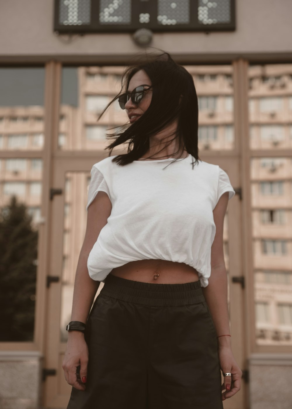woman wearing white blouse and sunglasses standing while glancing her right side