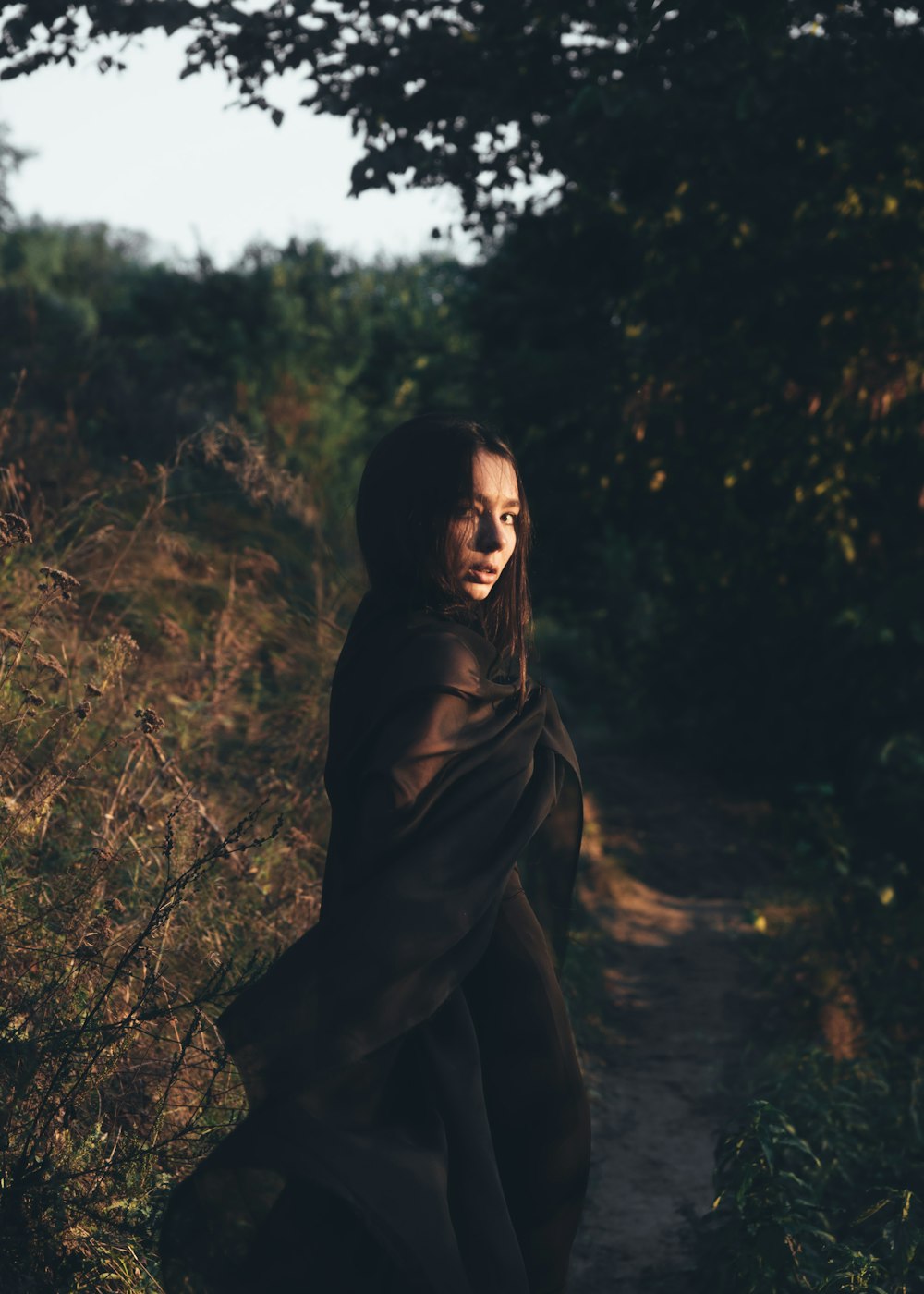 femme debout portant une robe noire pendant la journée