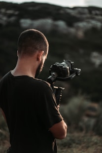 man holding DSLR camera taking photo of forest