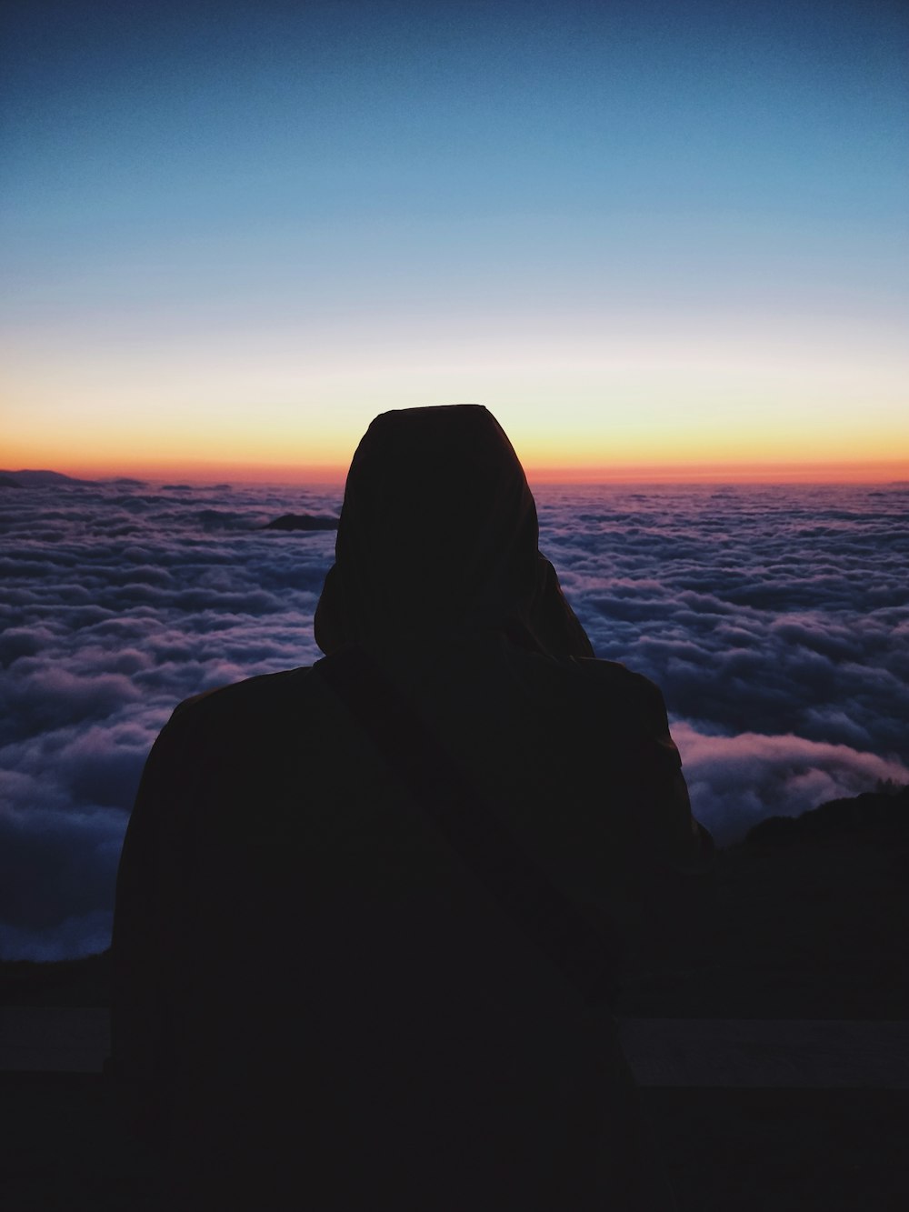 silhouette photo of person leaning forward overlooking sea of clouds