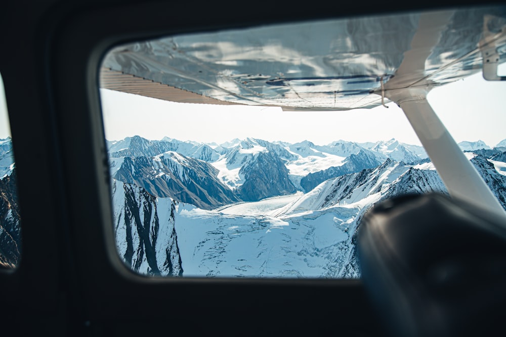 a view of a snowy mountain range from a plane window