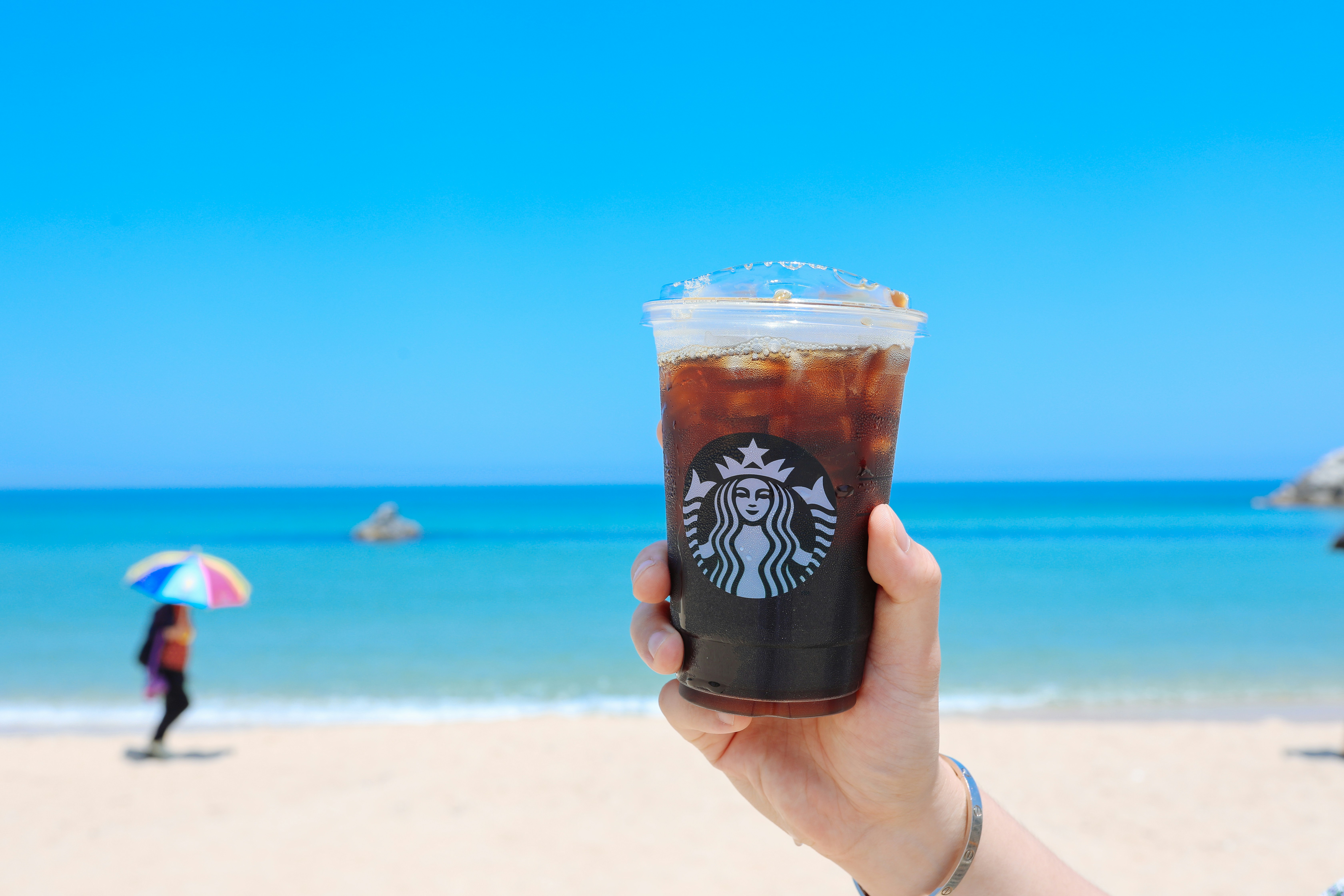 person holding clear StarBucks disposable cup