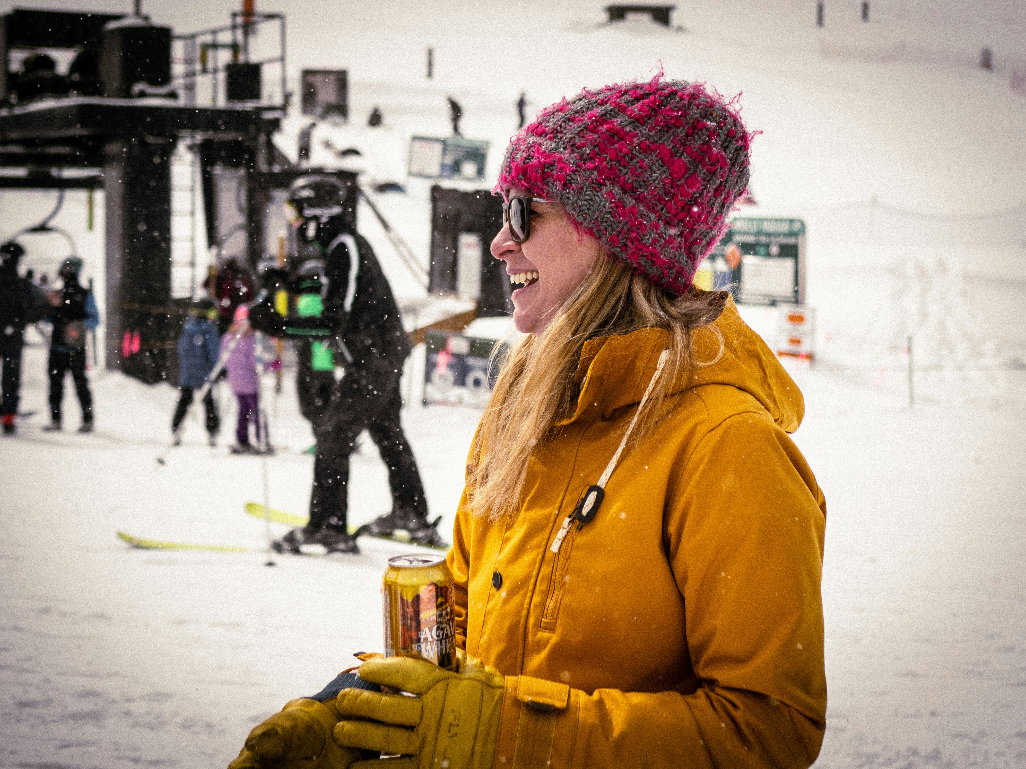 A woman enjoying a beer in the sun on the ski slopes