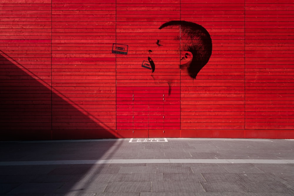 a red wall with a drawing of a man's face on it