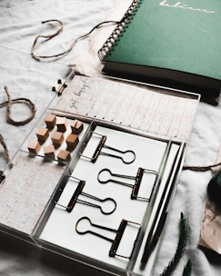 Close-up of organized office supplies including pens, notebooks, and folders with a wood background.
