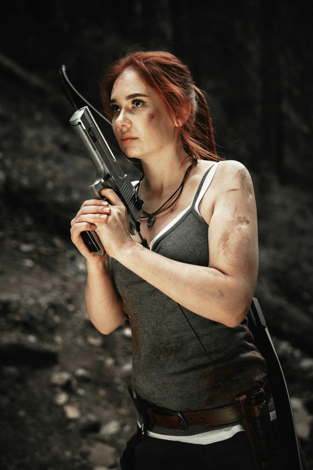 woman wearing gray spaghetti strap blouse holding gray rifle