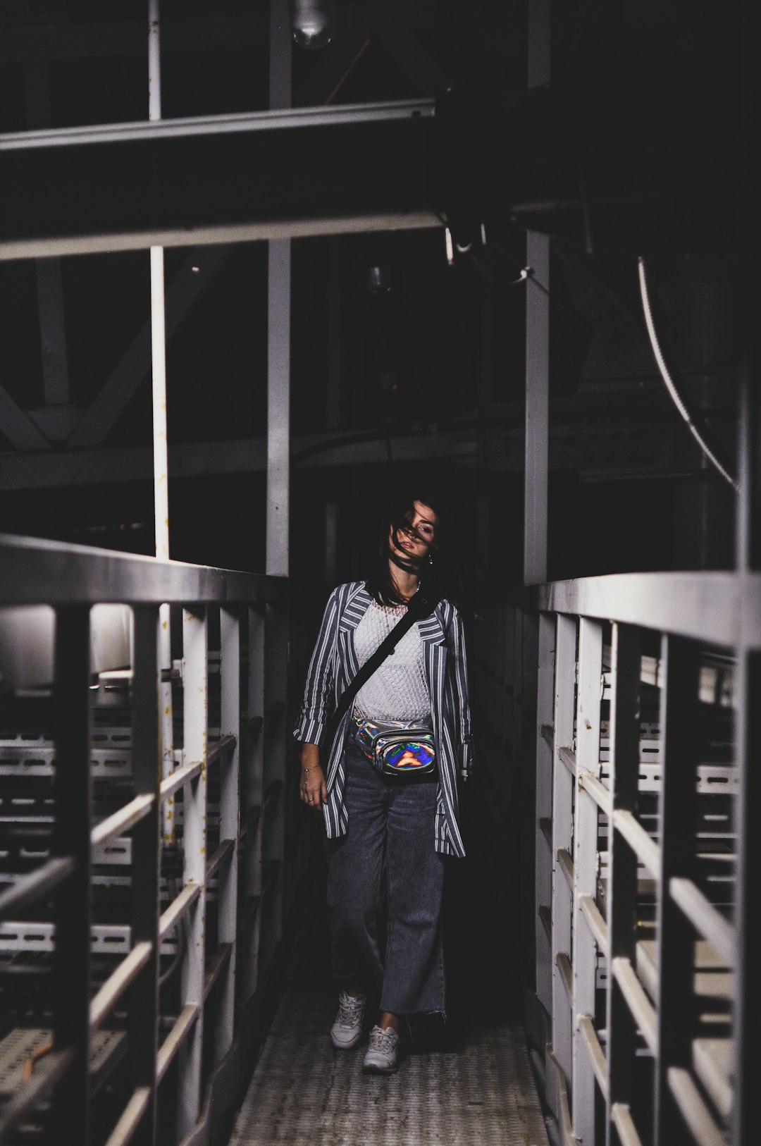 woman wearing black and white dress shirt and blue jeans walking on bridge