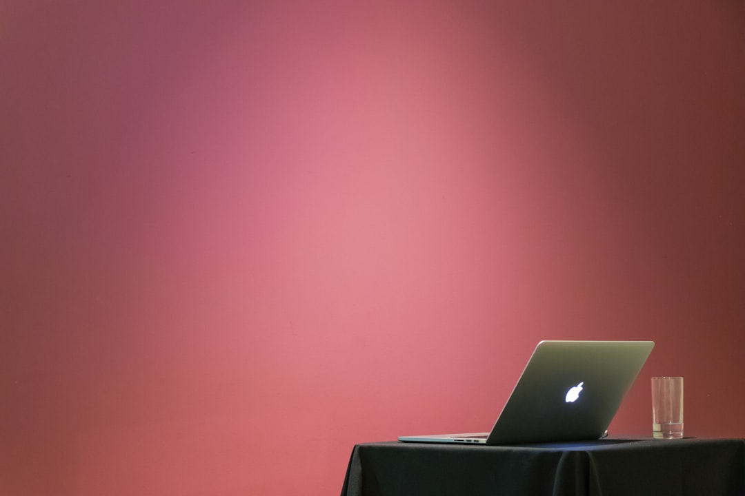 MacBook turned on beside clear drinking glass, Ready to present