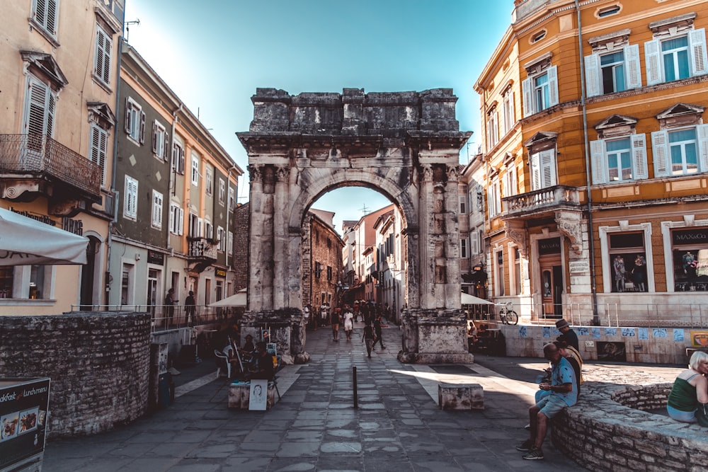 a woman sitting on a bench in front of a stone arch