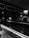 A dimly lit underground train platform with Victorian-style brickwork and signage indicating 'Baker Street'. The tracks are empty, and there is a blurred figure on the left side of the image. The atmosphere is subdued with a focus on shadows and light.