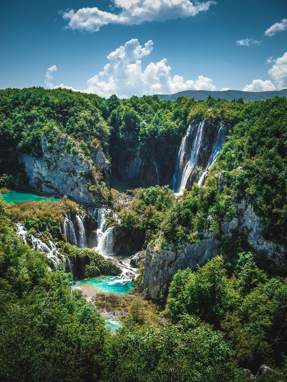 waterfalls surrounded by green trees during daytime