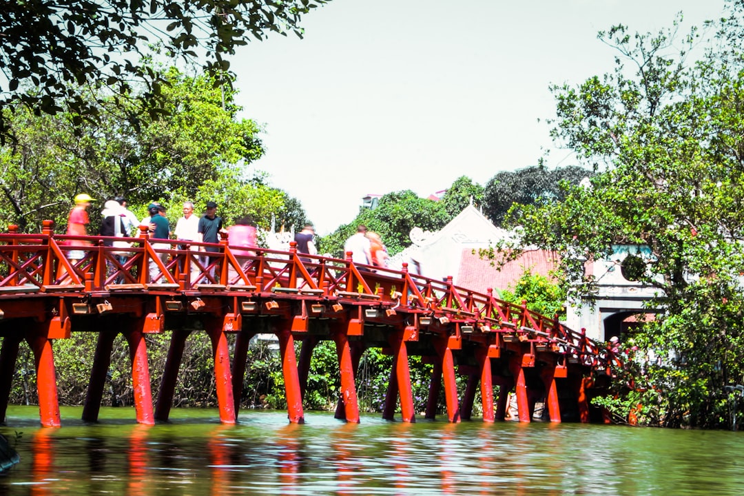 people standing on red wooden bridge during daytime