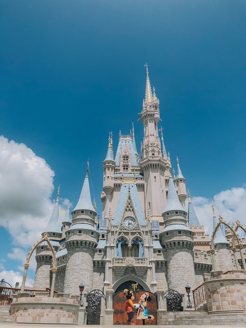 two persons wearing Disney Mickey and Minnie Mouse costumes in front of Disneyland Cinderella castle during day