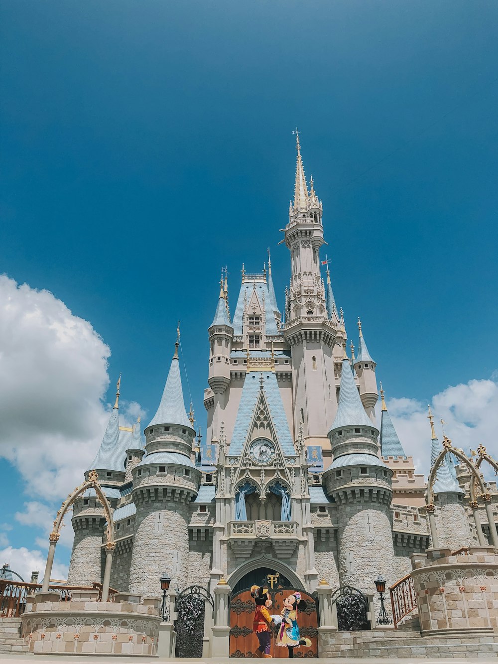 duas pessoas vestindo fantasias de Disney Mickey e Minnie Mouse em frente ao castelo da Cinderela da Disneyland durante o dia