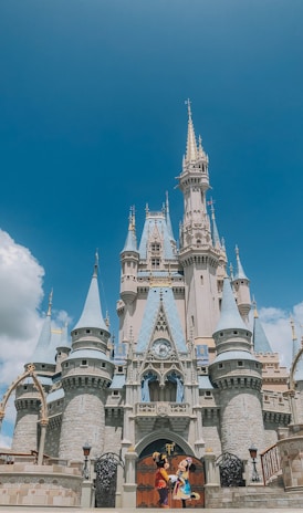 two persons wearing Disney Mickey and Minnie Mouse costumes in front of Disneyland Cinderella castle during day